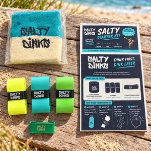 Salty Dinks starter pack with sweatband, three overgrips, paddle band and guide on driftwood